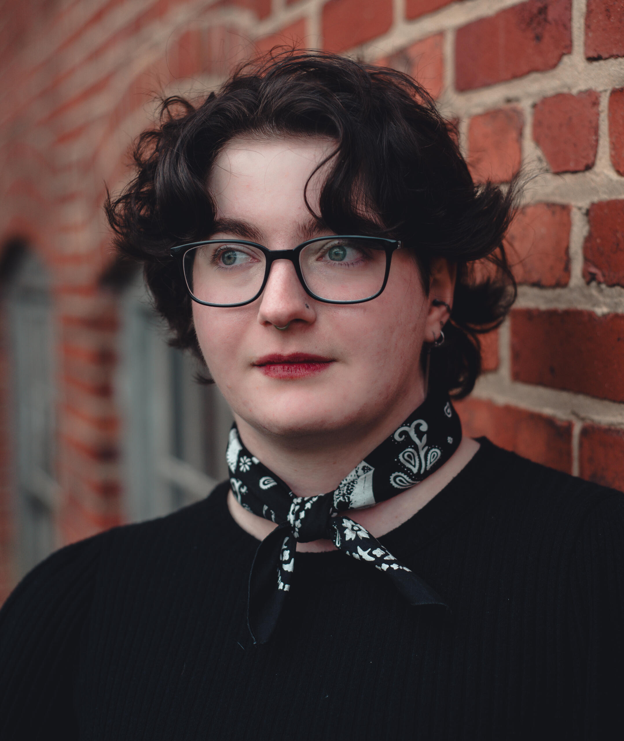 A black and white photo of a young white person with short dark hair and glasses.